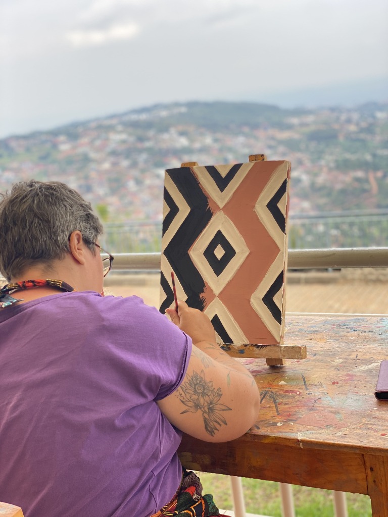 Guest painting Imigongo art with panoramic Kigali view
