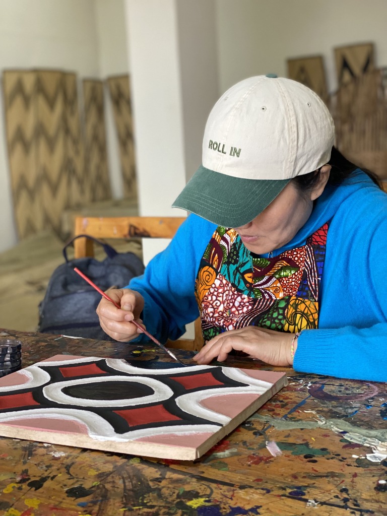 Artist painting in studio with traditional Imigongo art on walls